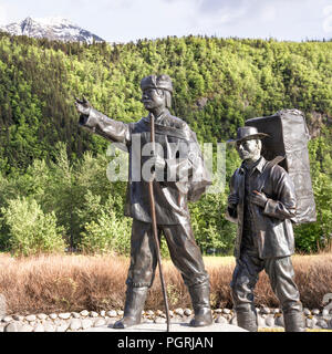 The Skagway Centennial Statue by Chuck Buchanan showing a typical prospector at the time of the Klondike Gold Rush being led by a native Tlingit guide Stock Photo