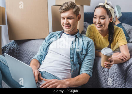 beautiful young couple using laptop at new home after relocation Stock Photo