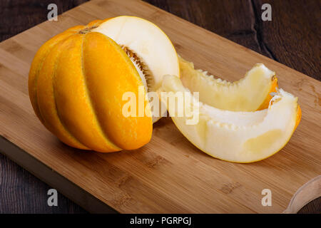 Melon with two cut slices on a cutting board Stock Photo