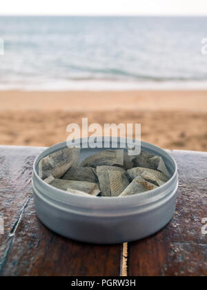 Swedish snus tobaco on a wood table in Thailand. Beach in background. Stock Photo