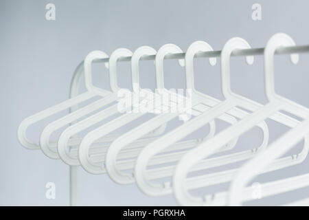 Clothing, costume and accessories concept - plastic hangers on a rod on white background Stock Photo