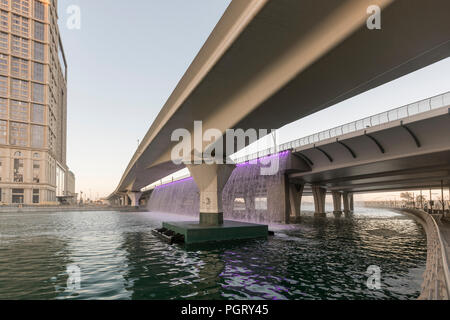 The  Dubai Water Canal waterfall, where the canal meets Sheikh Zayed Road, during the day, Dubai, UAE Stock Photo