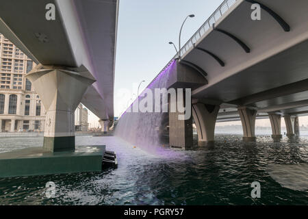 The  Dubai Water Canal waterfall, where the canal meets Sheikh Zayed Road, during the day, Dubai, UAE Stock Photo