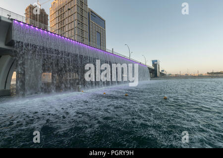 The  Dubai Water Canal waterfall, where the canal meets Sheikh Zayed Road, during the day, Dubai, UAE Stock Photo