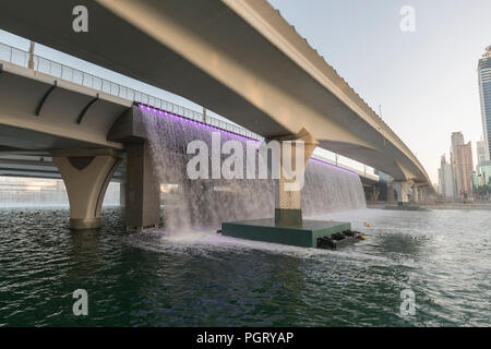 The  Dubai Water Canal waterfall, where the canal meets Sheikh Zayed Road, during the day, Dubai, UAE Stock Photo