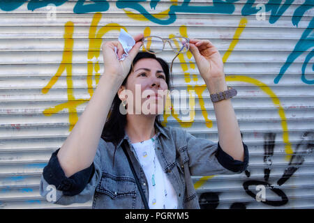 Young adult woman cleaning glasses on the street, Stock Photo