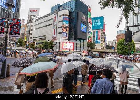 People cross the busy Shibuya intersection in Tokyo on a rainy day. Stock Photo