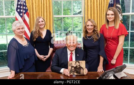 U.S President Donald Trump poses with the family of Medal of Honor recipient Tech. Sgt. John Chapman in the Oval Office of the White House August 22, 2018 in Washington, DC. Standing from left to right are: Chapman’s mother Teresa Chapman, daughter Madison Chapman, wife Valerie Nessel and daughter Brianna Chapman. Stock Photo