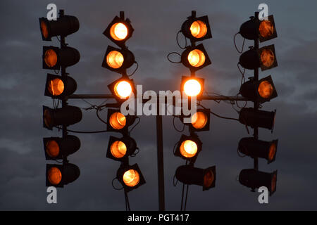 spotlight at music event with dark grey sky by night, red floodlights flash lights background Stock Photo