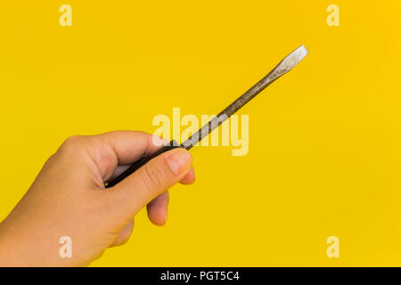 hand holding a screwdriver on a yellow background Stock Photo