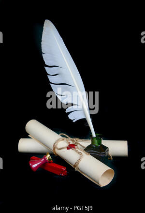 White feather in the inkwell, sealing wax, signet and two paper scroll isolated on black background Stock Photo