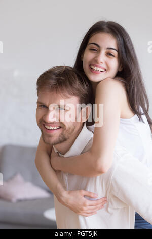 Happy young girlfriend piggyback smiling boyfriend having fun at Stock Photo