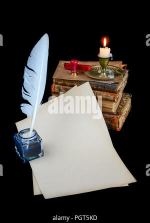 Still life with sheets of old paper, pen, a lighted candle in copper candlestick and a pile of old books isolated on a background Stock Photo