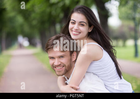 Portrait of smiling young girlfriend piggyback millennial boyfri Stock Photo