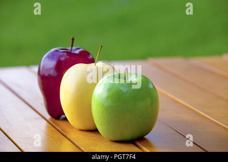 Three apples on a table red and golden delicious and granny smith Stock Photo