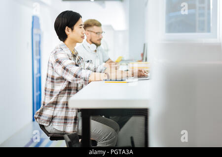 Two man sitting in coworking space and using their modern gadgets Stock Photo