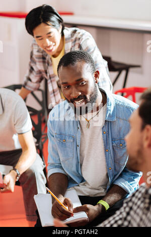 Cheerful man smiling and making notes while studying Stock Photo