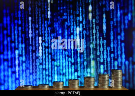 secured internet business. big coin piles in front of blue binary code computer screen. rich through savings account online. Stock Photo