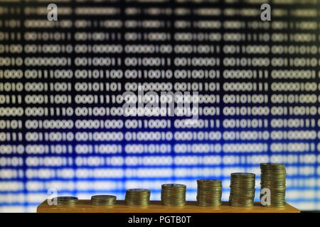 secured internet business. big coin piles in front of blue binary code computer screen. rich through savings account online. Stock Photo