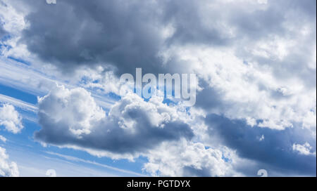 against the background of the blue sky, fluffy clouds of white and gray color, bizarre shapes created by nature Stock Photo