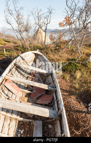 Old wooden dinghy rowboat beached on grass viewed close up on the prow with detail of the hull against a blue sky Stock Photo