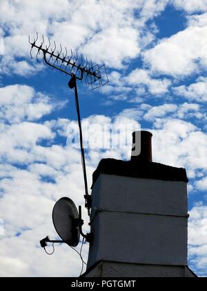 Chimney with antenna and satellite dish against a cloudy sky in Edinburgh, Scotland. Stock Photo