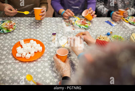 hands with spoons and plastic cups making sweets on colorful plates Stock Photo
