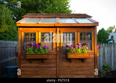 Cedar garden shed illuminated by a summer sunset. Stock Photo