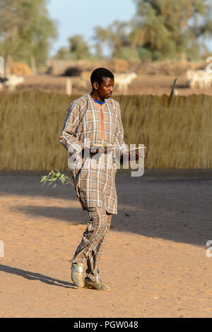 FERLO DESERT, SENEGAL - APR 25, 2017: Unidentified Fulani man walks along the street. Fulanis (Peul) are the largest tribe in West African savannahs Stock Photo