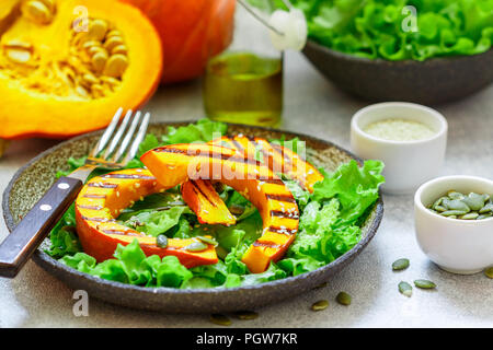 Delicious light salad of grilled pumpkin slices and lettuce with sesame seeds, lemon juice and olive oil. Healthy diet, vegetarian snack. Selective fo Stock Photo