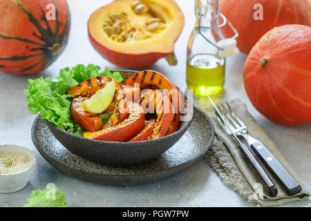 Delicious light salad of grilled pumpkin slices and lettuce with sesame seeds, lemon juice and olive oil. Healthy diet, vegetarian snack. Selective fo Stock Photo