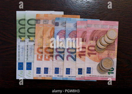 Euro Bills and Coins Laying Flat on a Dark Wood Table Stock Photo