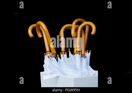 A set of white modern umbrellas isolated on a black background. Stock Photo