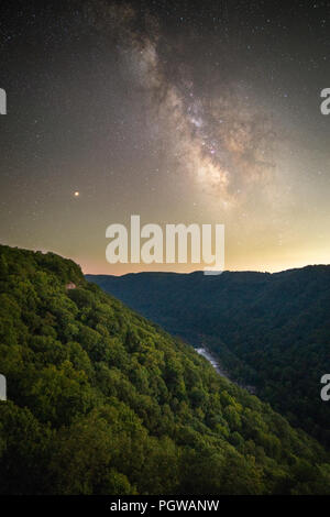 The Milky Way and the red planet mars stand above an exposed buttress of the Endless Wall in West Virginia's New River Gorge. Stock Photo