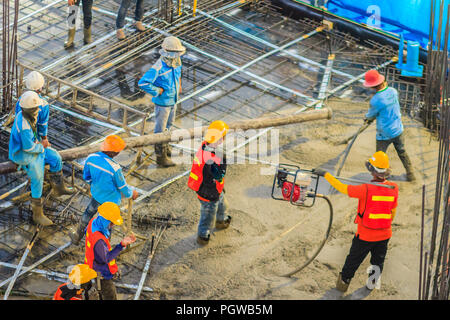 Construction workers using a concrete vibrator (gasoline engine type) at the construction site to compact the liquid concrete in reinforcement form wo Stock Photo