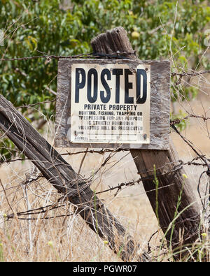 No trespassing, No hunting, No fishing, No trapping sign on fence post on rural private property - California USA