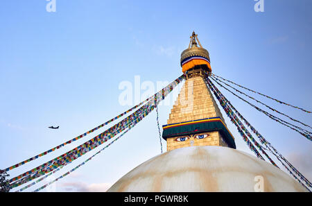 Bodnath Buddhist Stupa with prayer flags and airplane in Kathmandu Stock Photo