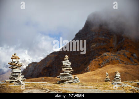 Small piles from stones on the Mardi Himal trek and cloudy peaks of Himalaya Mountains in Nepal Stock Photo