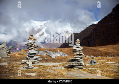 Small piles from stones on the Mardi Himal trek and cloudy peaks of Himalaya Mountains in Nepal Stock Photo