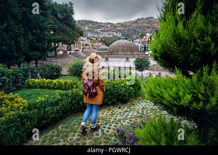 Beautiful woman in brown hat and jacket near the dome of Public Sulfuric bath district in central Tbilisi, Georgia Stock Photo