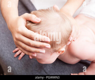 Seven month baby girl skull and neck are manipulated by osteopathic or chiropractic manual therapist Stock Photo