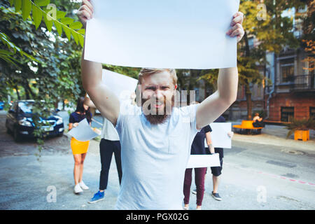 Group of protesting young people outdoors. The protest, people, demonstration, democracy, fight, rights, protesting concept. The caucasian men and womem holding empty posters or banners with copy space Stock Photo