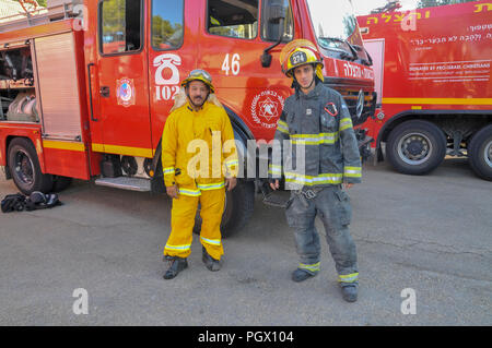 Fire trucks in a fire station, Haifa, Israel. The yellow protective clothing (left) is used during forest fires while the black coat is used in urban Stock Photo