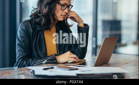 Busy woman sitting on desk and working on laptop. Asian businesswoman working on laptop computer at office. Stock Photo