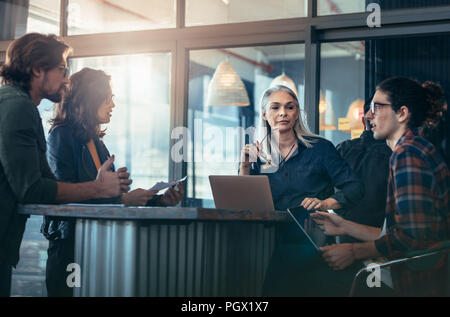 Group of business people standing around a table and having a meeting. business team discussing work in office. Stock Photo