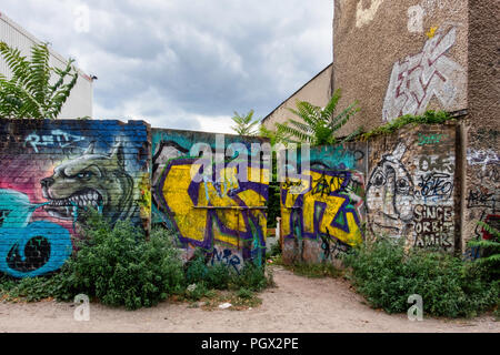 Berlin, Friedrichshain. Street view of old building and brick wall covered in graffiti tags and Street art Stock Photo