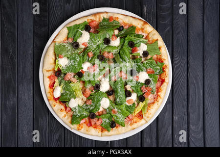 Top view of pizza with ham, feta cheese, anchovy and lettuce salad Stock Photo