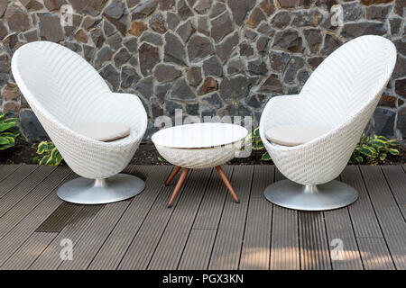 Modern white armchairs and table, modern garden furniture. Cozy space for relax in the garden Stock Photo