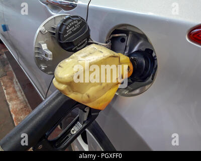 Fuel nozzles adding gasoline fuel in car at a pump gas station.