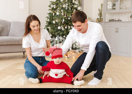Parents playing with baby near Christmas tree Stock Photo